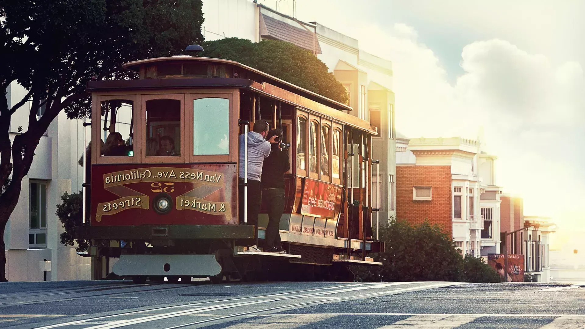 Un tram costeggia una collina a San Francisco, mentre i passeggeri guardano fuori dal finestrino.