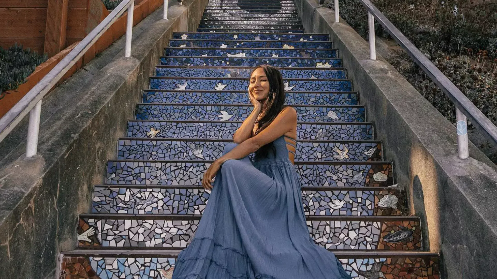 A woman poses sitting on the 16th Avenue tiled stairs in the Sunset neighborhood of San Francisco.